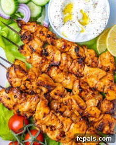 top view chicken skewers on a plate with a side of yogurt garlic dip