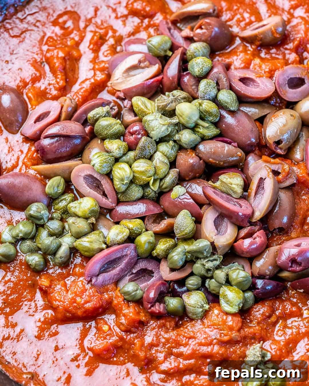 Rustic Chicken Puttanesca 6 puttanesca sauce in pan with capers and sliced kalamata olives