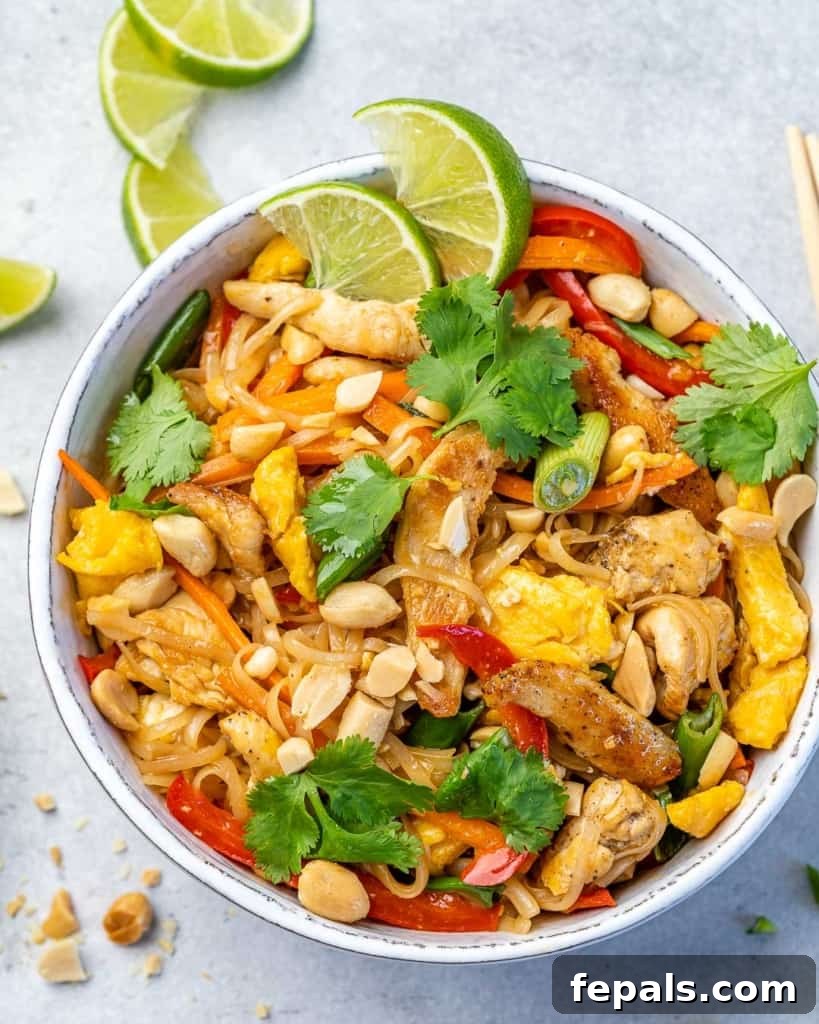 Signature Chicken Pad Thai 5 Overhead shot of a delicious bowl of chicken pad thai, garnished with chopped peanuts and a lime wedge, presented in a clean white bowl.