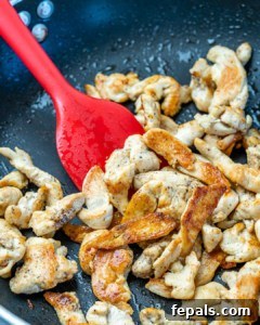 Signature Chicken Pad Thai 8 Chicken being cooked in a skillet, sizzling and browning to perfection.