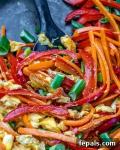 Signature Chicken Pad Thai 9 Close-up view of vibrant sautéed bell peppers, carrots, green onions, and garlic alongside perfectly scrambled egg in a hot pan.