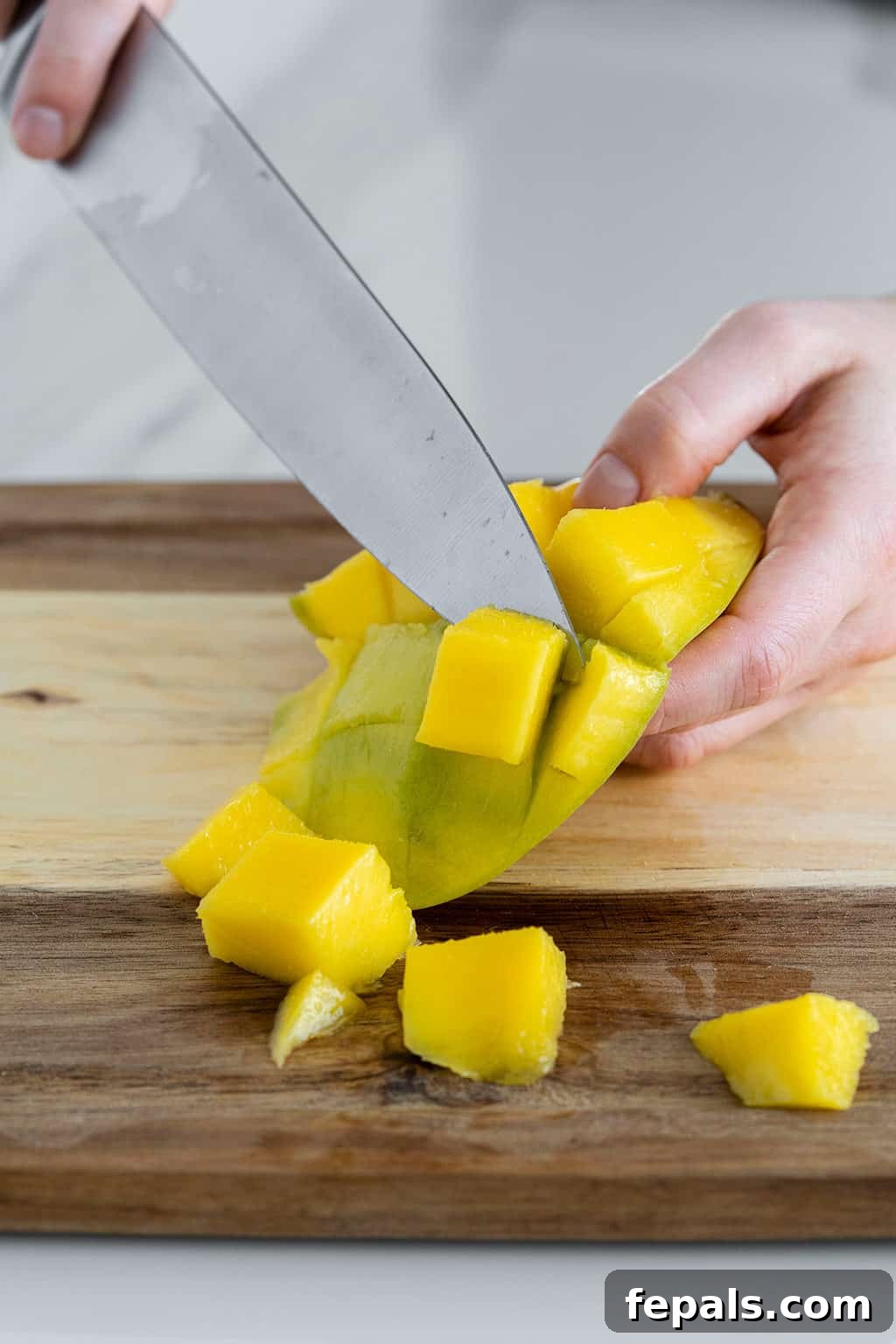 Knife slicing off mango piece off skin, another method to remove the flesh
