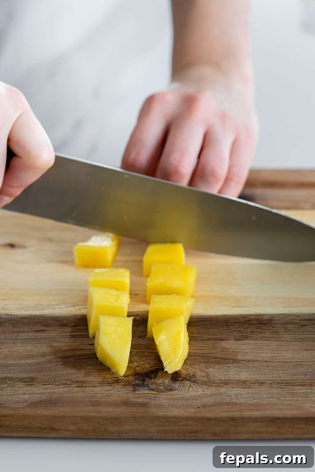 Close-up of mango slices being cut into cubes, showcasing the final dicing step