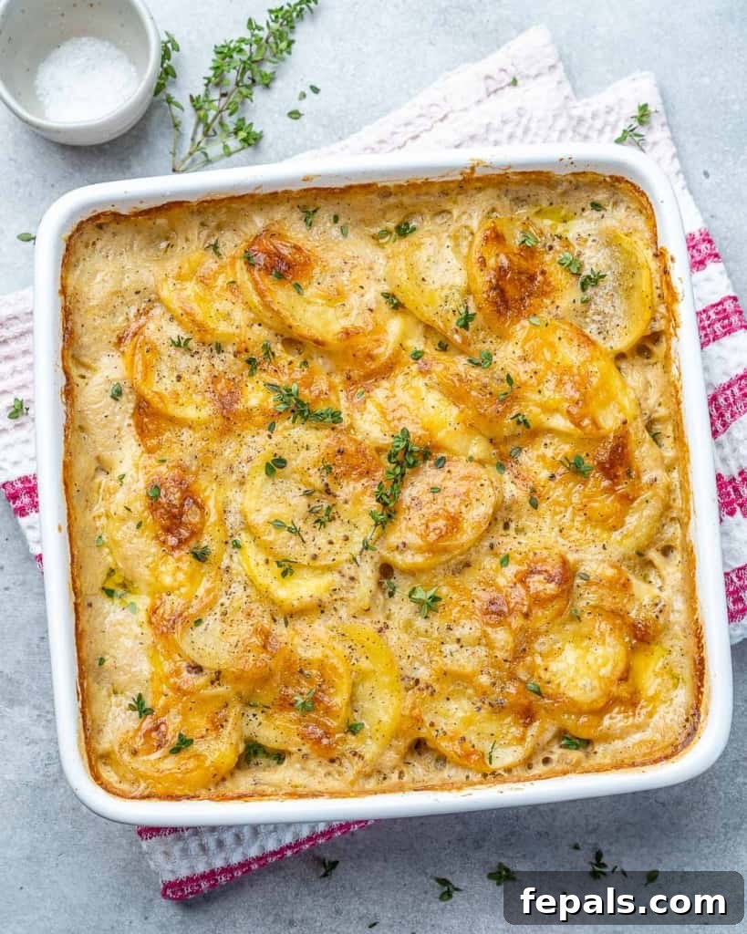Effortless Cheesy Potato Gratin 2 Top view of golden brown potato au gratin in a white baking dish, garnished with fresh herbs.