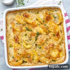 Effortless Cheesy Potato Gratin 12 Top view of golden brown potato au gratin in a white baking dish, garnished with fresh herbs.