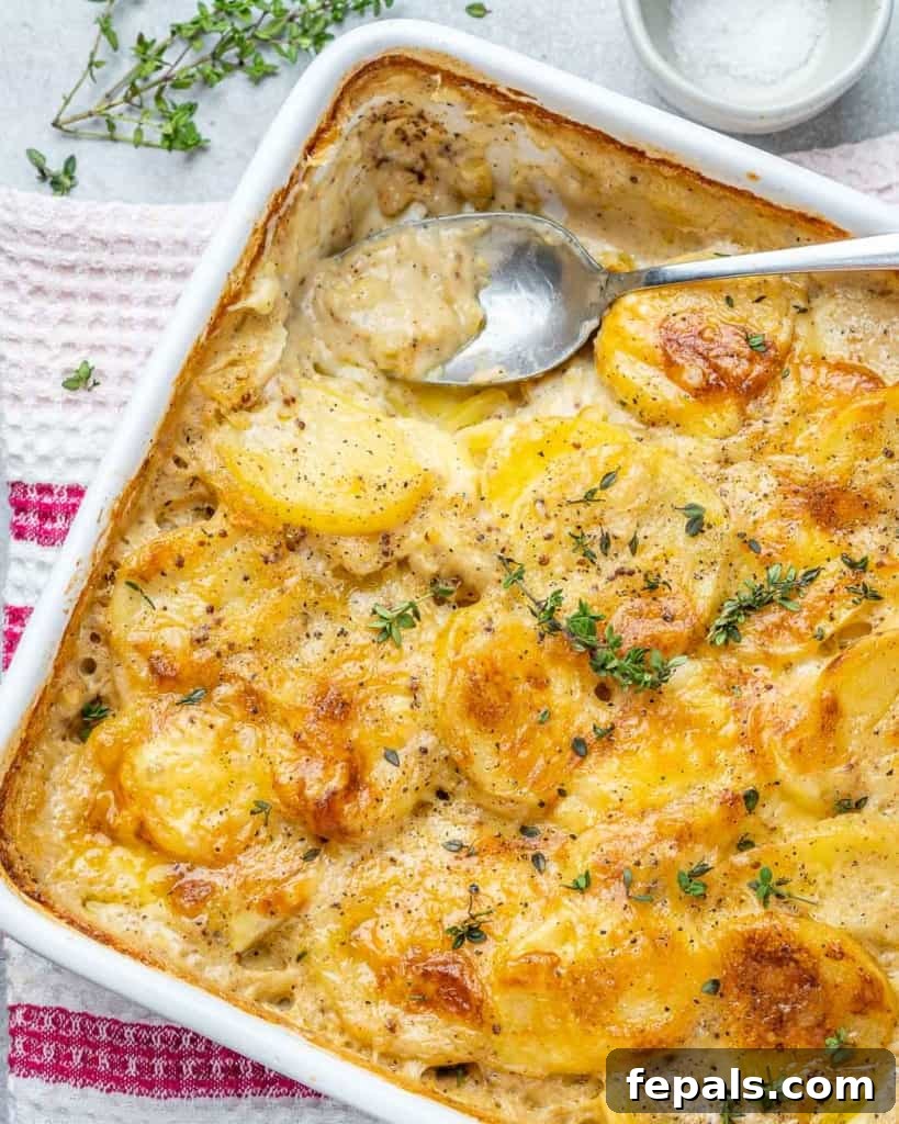 Effortless Cheesy Potato Gratin 8 Close-up of a serving spoon scooping out a portion of baked potato au gratin from the dish.