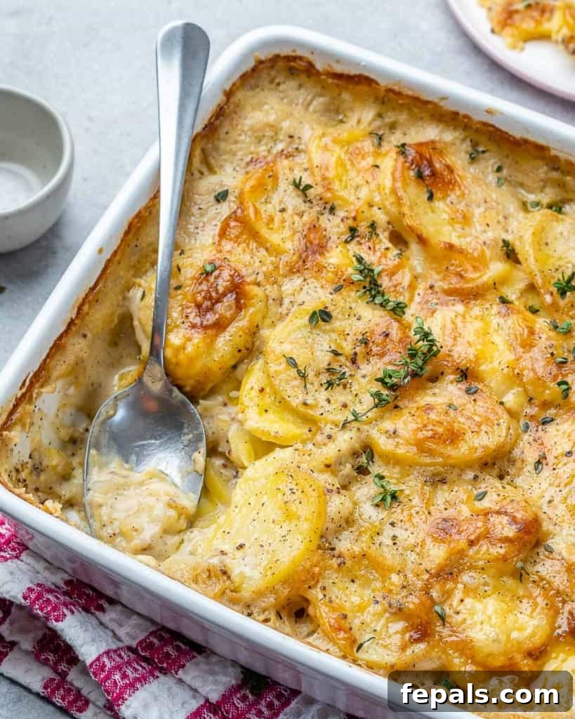 Effortless Cheesy Potato Gratin 10 Side shot of a baked potato au gratin in a white dish, showing its layered texture and golden crust.