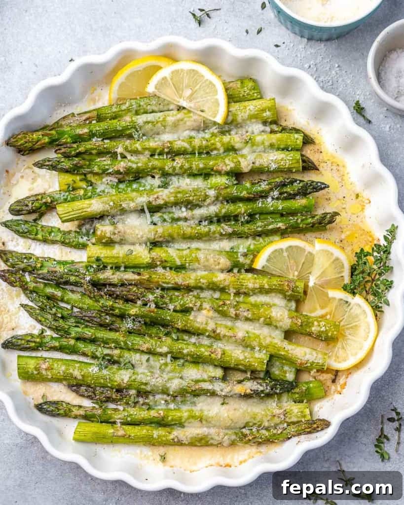 Parmesan Crusted Asparagus 2 top view of baked asparagus in a white dish with lemon garnishes