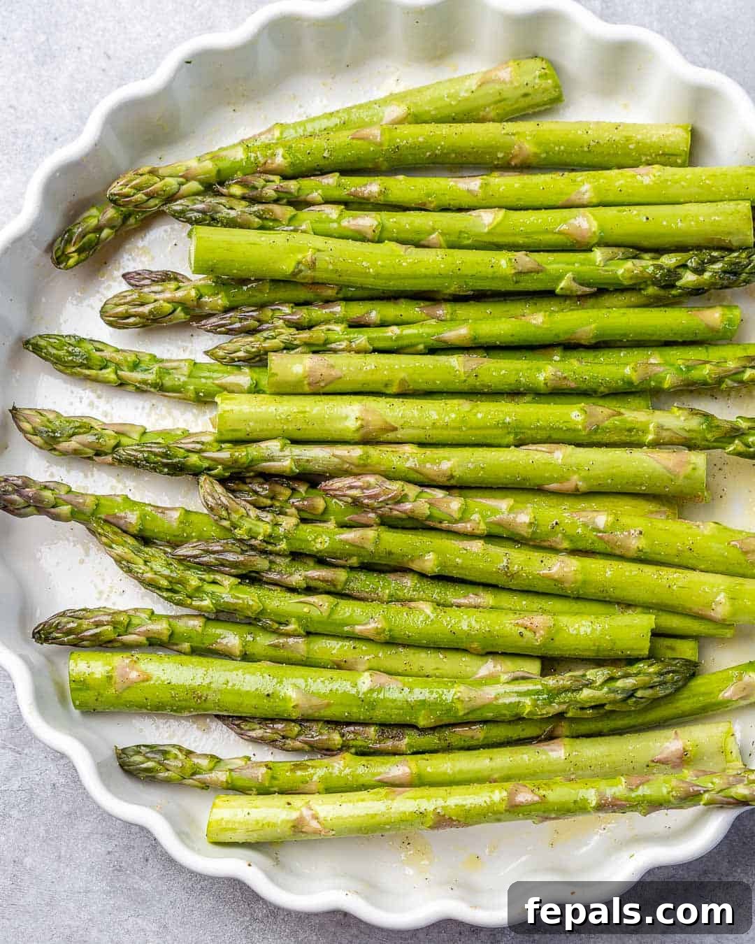Parmesan Crusted Asparagus 6 uncooked asparagus on a white dish