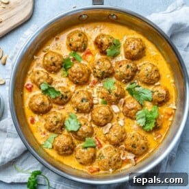 Turkey meatballs in a curry sauce in a stainless steal round pan.