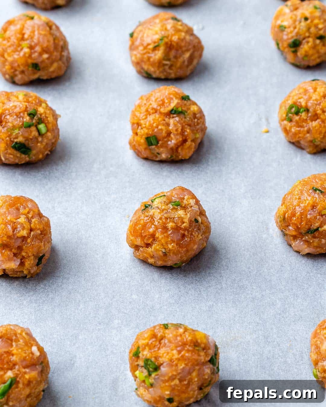 meatballs place on a pan before baking.