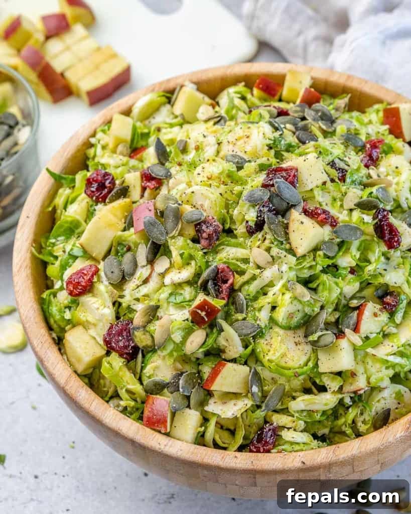 Elevated Shaved Brussels Salad 7 A brown bowl filled with a fresh, vibrant Brussels sprouts salad, presented at an angle.