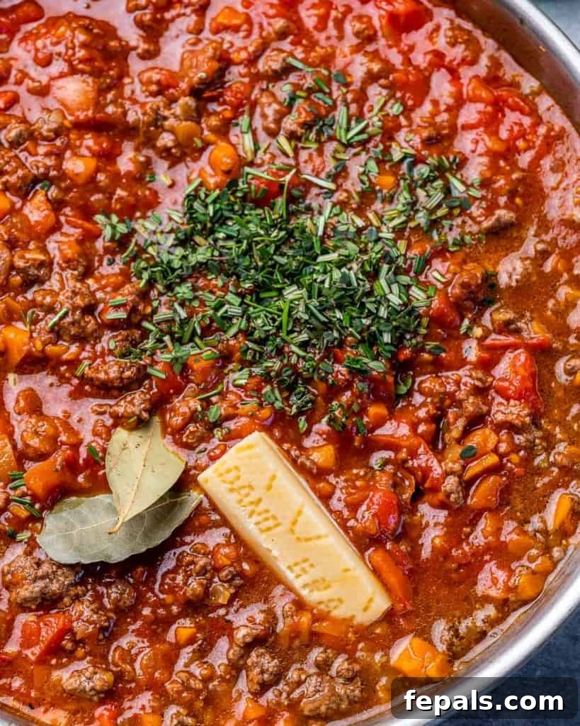 Hearty Beef Bolognese 6 Adding herbs and parmesan to bolognese.