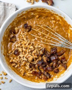 nuts and dates over batter in a white bowl