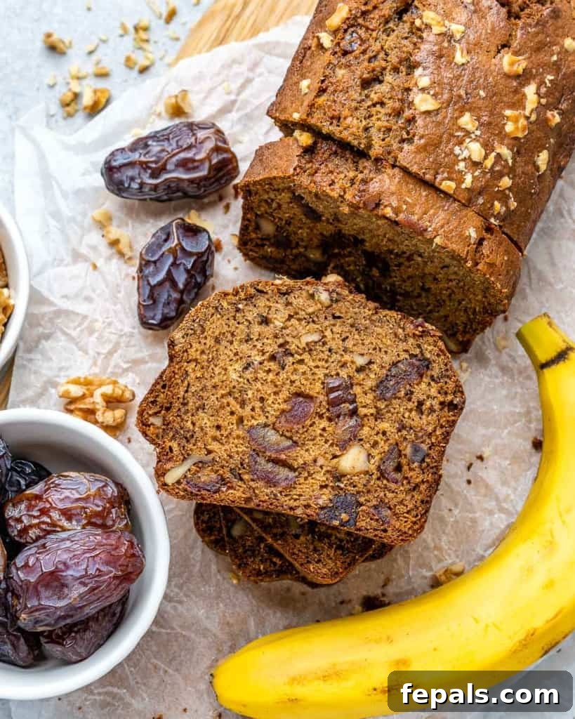 Top view of an entire banana date nut bread loaf on a cutting board, surrounded by slices.