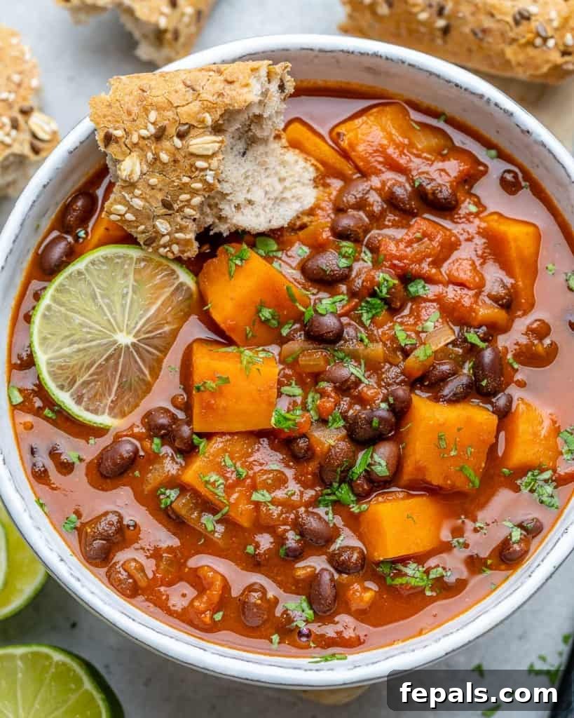 Comforting Sweet Potato Chili 2 A vibrant top-down shot of sweet potato chili in a white bowl, garnished with fresh lime wedges and cilantro, ready to be enjoyed.