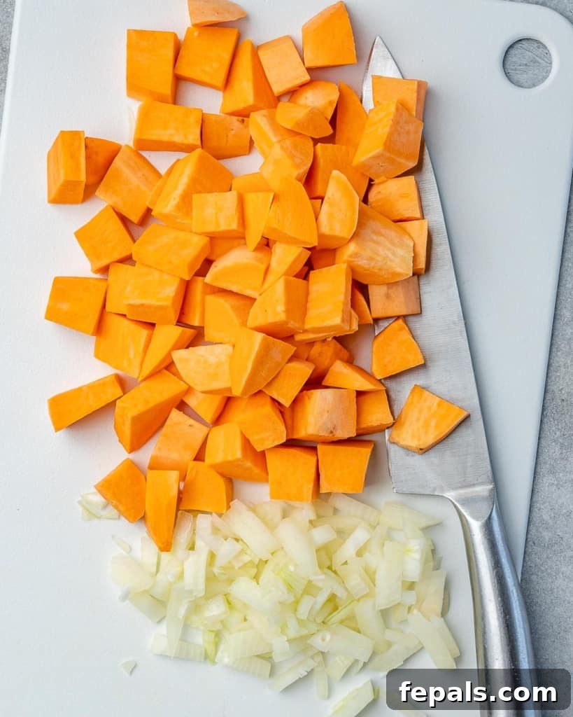 Comforting Sweet Potato Chili 5 Freshly chopped onions and diced sweet potatoes arranged on a wooden cutting board with a knife, highlighting the initial preparation steps for the chili.