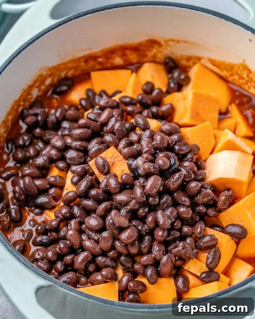 Comforting Sweet Potato Chili 6 Close-up shot of black beans and diced sweet potatoes simmering in a pot, capturing the rich textures and vibrant colors as they cook into chili.