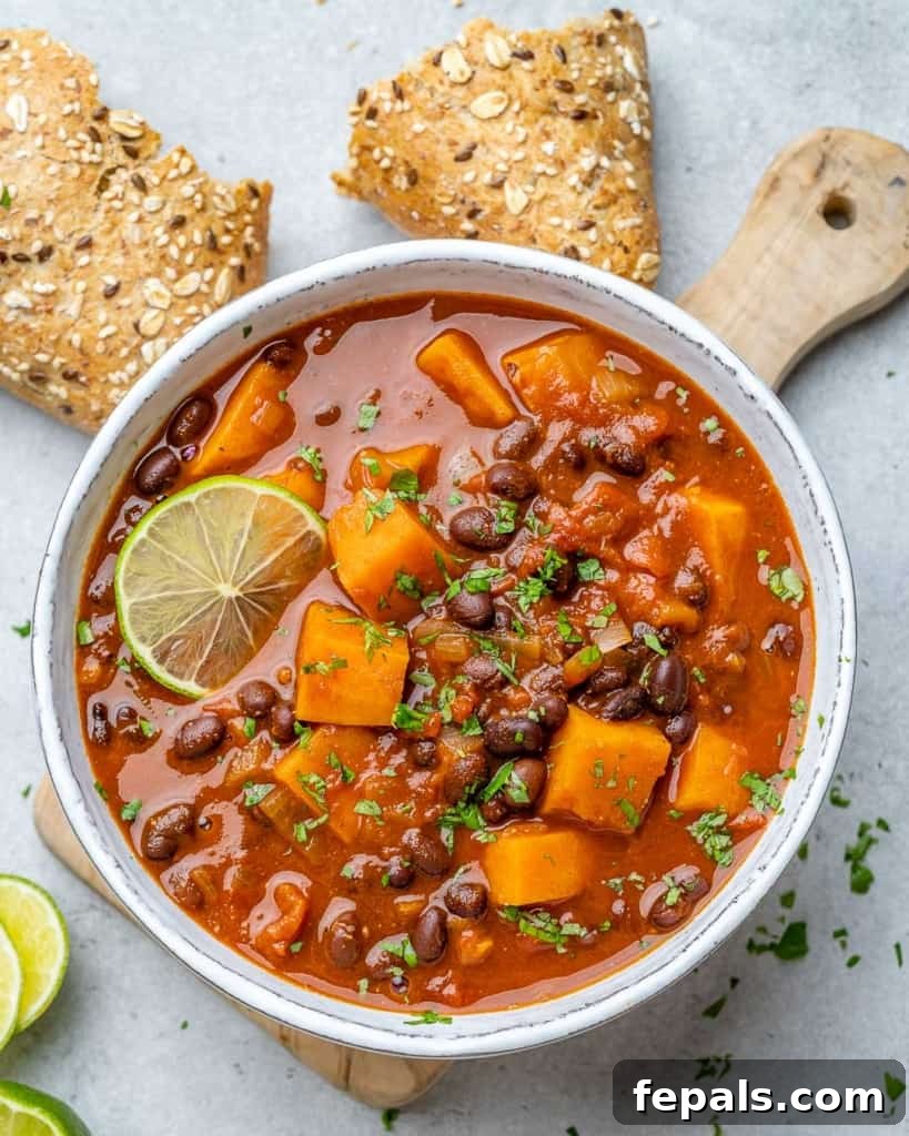 Comforting Sweet Potato Chili 8 An overhead view of a hearty bowl of sweet potato chili, served in a white bowl, with a generous side of crusty bread for dipping.