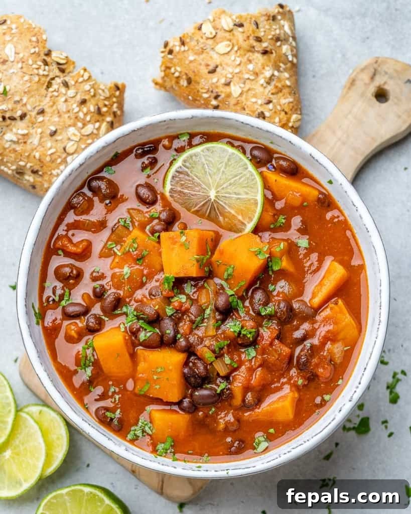 Comforting Sweet Potato Chili 9 A beautifully composed top-down view of sweet potato chili in a white bowl, with a side of crusty bread, showcasing its hearty and inviting nature.