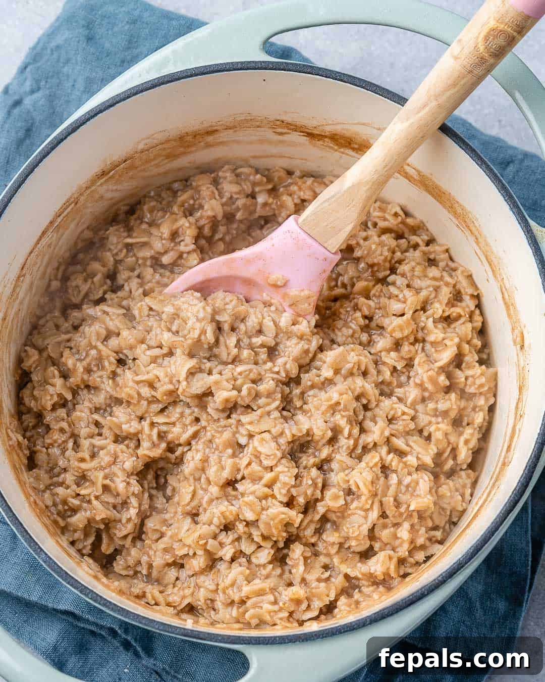 Nutty Oatmeal Morning Fuel 5 Close-up shot of a pot on a stovetop, with oatmeal being stirred by a spoon.