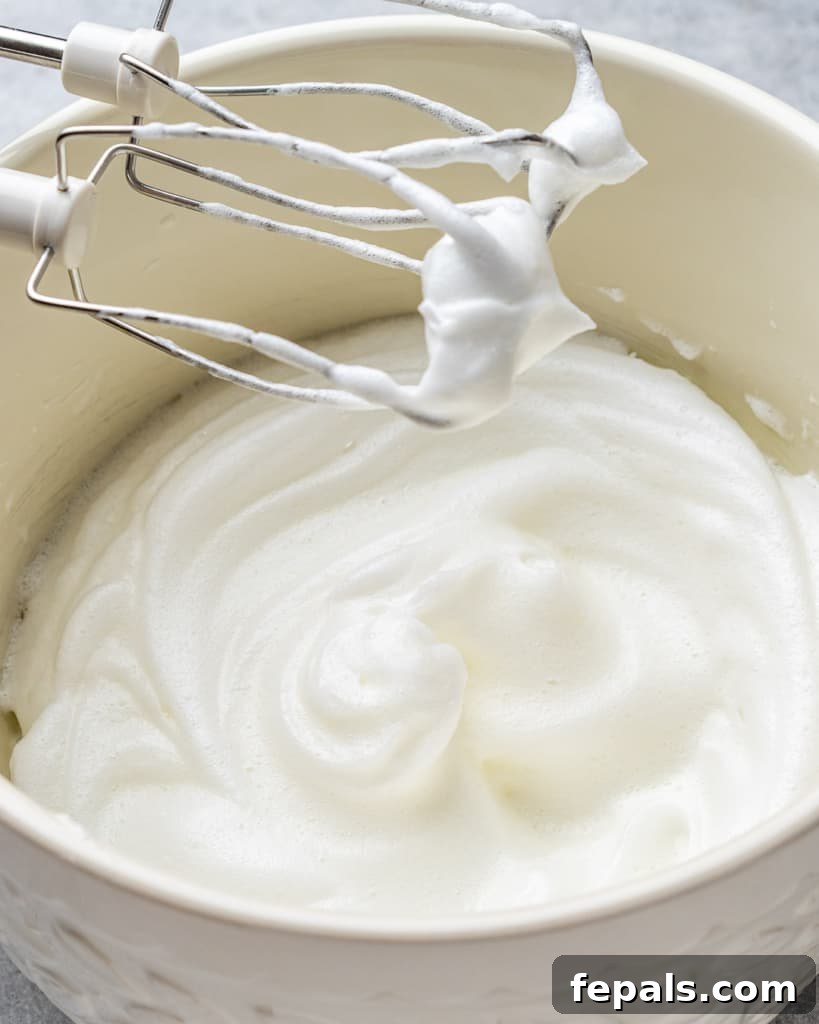 Effortless Keto Waffles 5 Close-up of egg whites perfectly whipped to stiff peaks in a mixing bowl, ready to be folded into the batter.