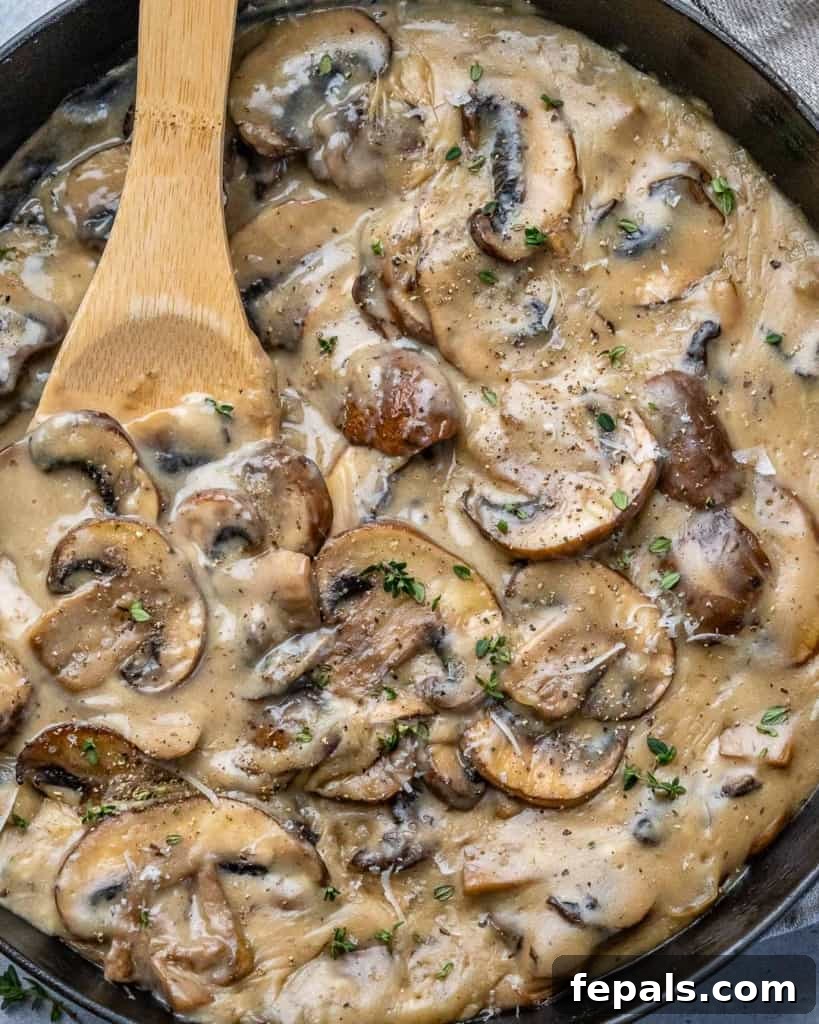 Mushrooms in sauce in cast iron skillet with spoon