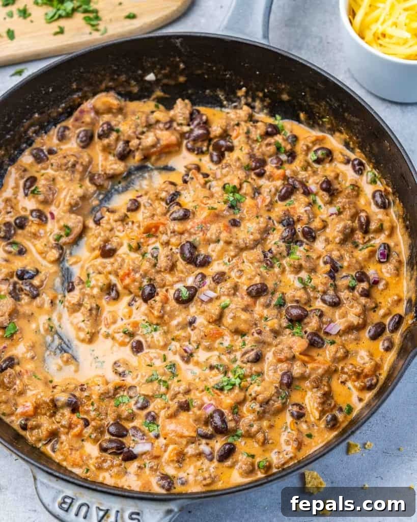 Rancher's Rustic Queso 2 Top view of a bubbling, rich cowboy queso dip served in a rustic black cast iron pan, garnished with fresh cilantro and ready to be scooped