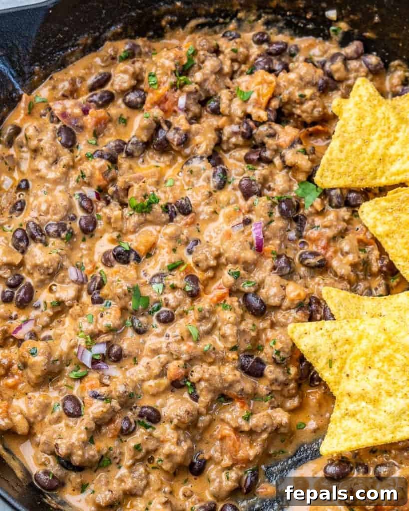 Rancher's Rustic Queso 8 An inviting close-up shot of the rich, melted cheese and hearty ingredients within the cowboy queso dip, showcasing its enticing texture and vibrant colors