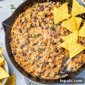 Close-up top view of creamy cowboy queso dip served in a bowl with golden tortilla chips for dipping