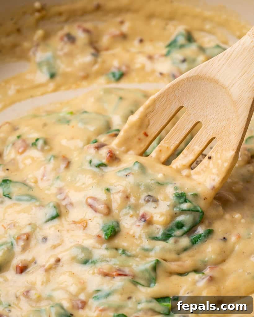 Creamy Chicken Spinach Pasta 6 Wooden spoon stirring chicken and spinach mixture