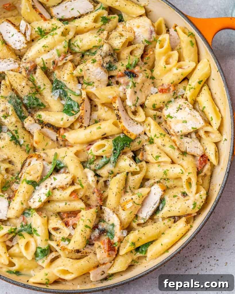 Creamy Chicken Spinach Pasta 8 Orange skillet filled with chicken and pasta with spinach
