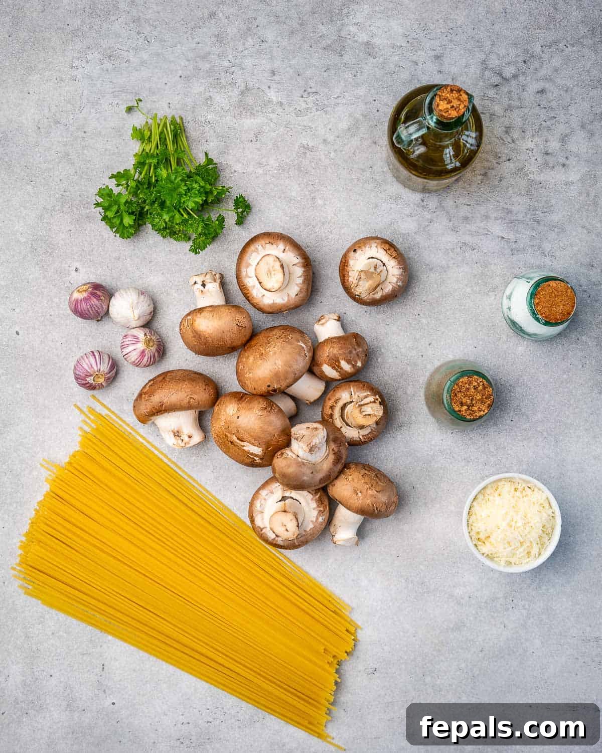 A colorful array of fresh ingredients including spaghetti, mushrooms, garlic, cheese, and parsley, ready to be transformed into a delicious meal.