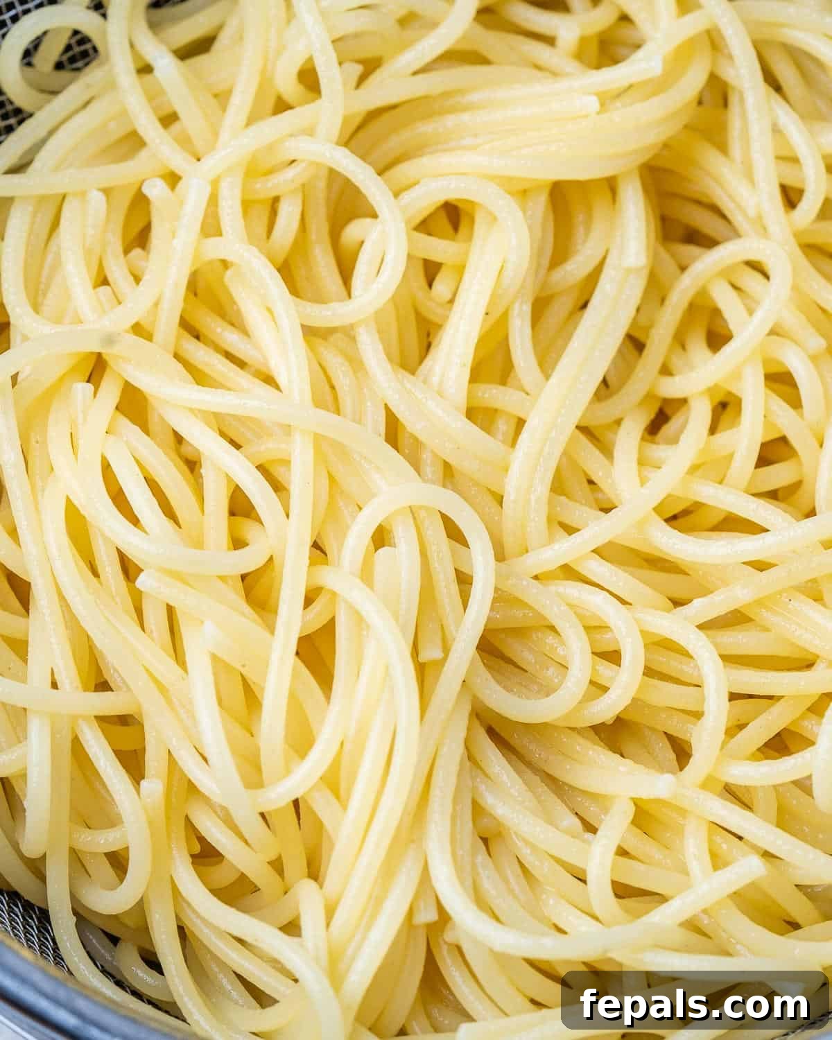 A close-up of perfectly cooked spaghetti noodles, glistening and ready for sauce.