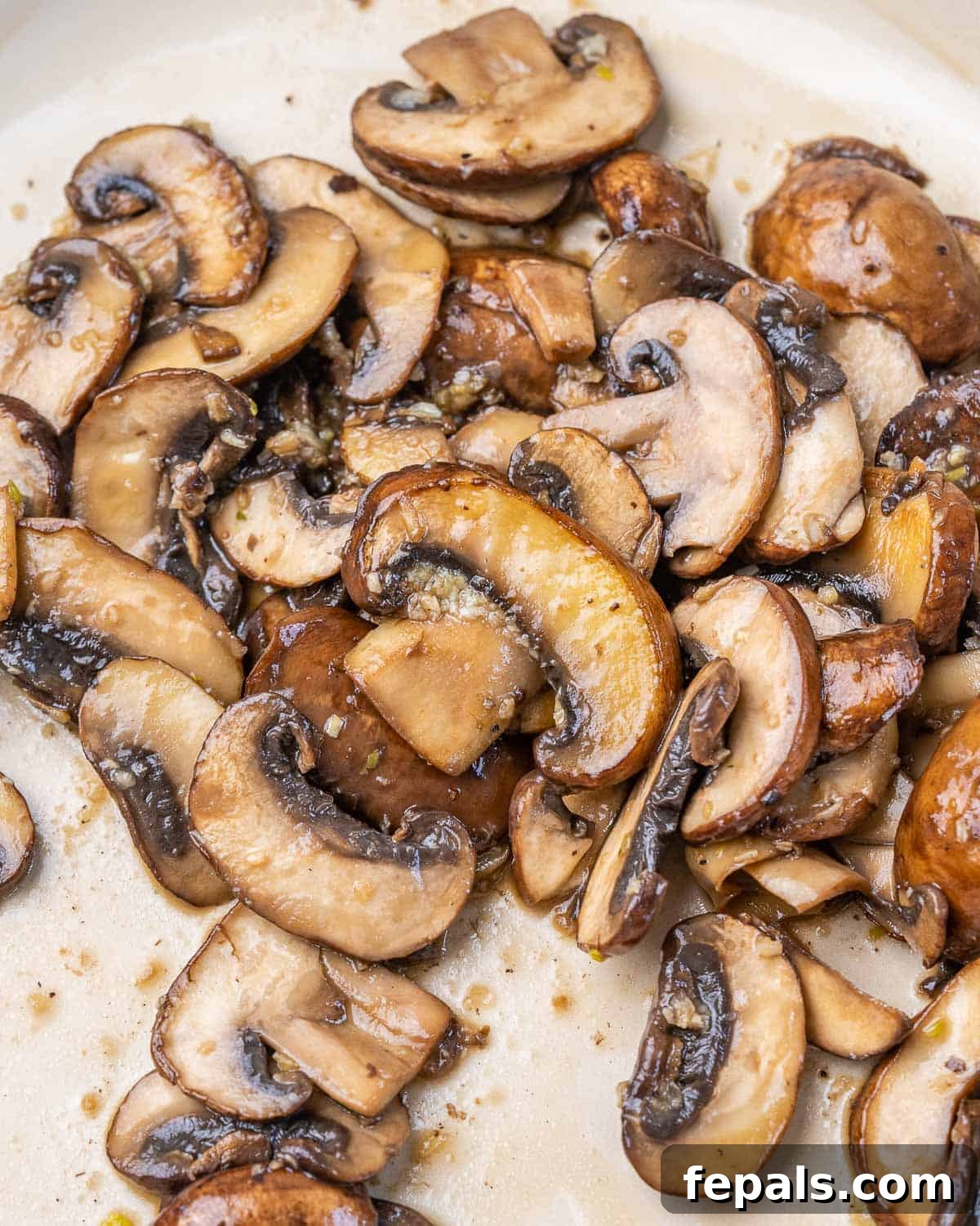 Sautéed sliced mushrooms browning beautifully in a skillet, releasing their rich aroma.