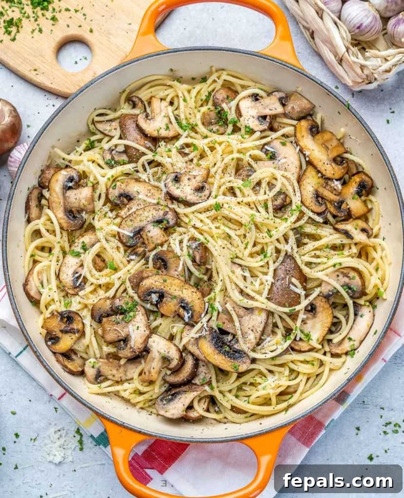 An inviting top-down shot of mushroom pasta served in an orange skillet, highlighting its fresh ingredients.