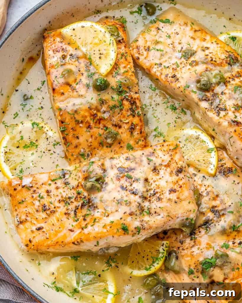 Zesty Salmon Piccata 10 Close-up side shot of beautifully seared salmon fillets coated in a lemon caper sauce, garnished with fresh capers and bright lemon wedges.