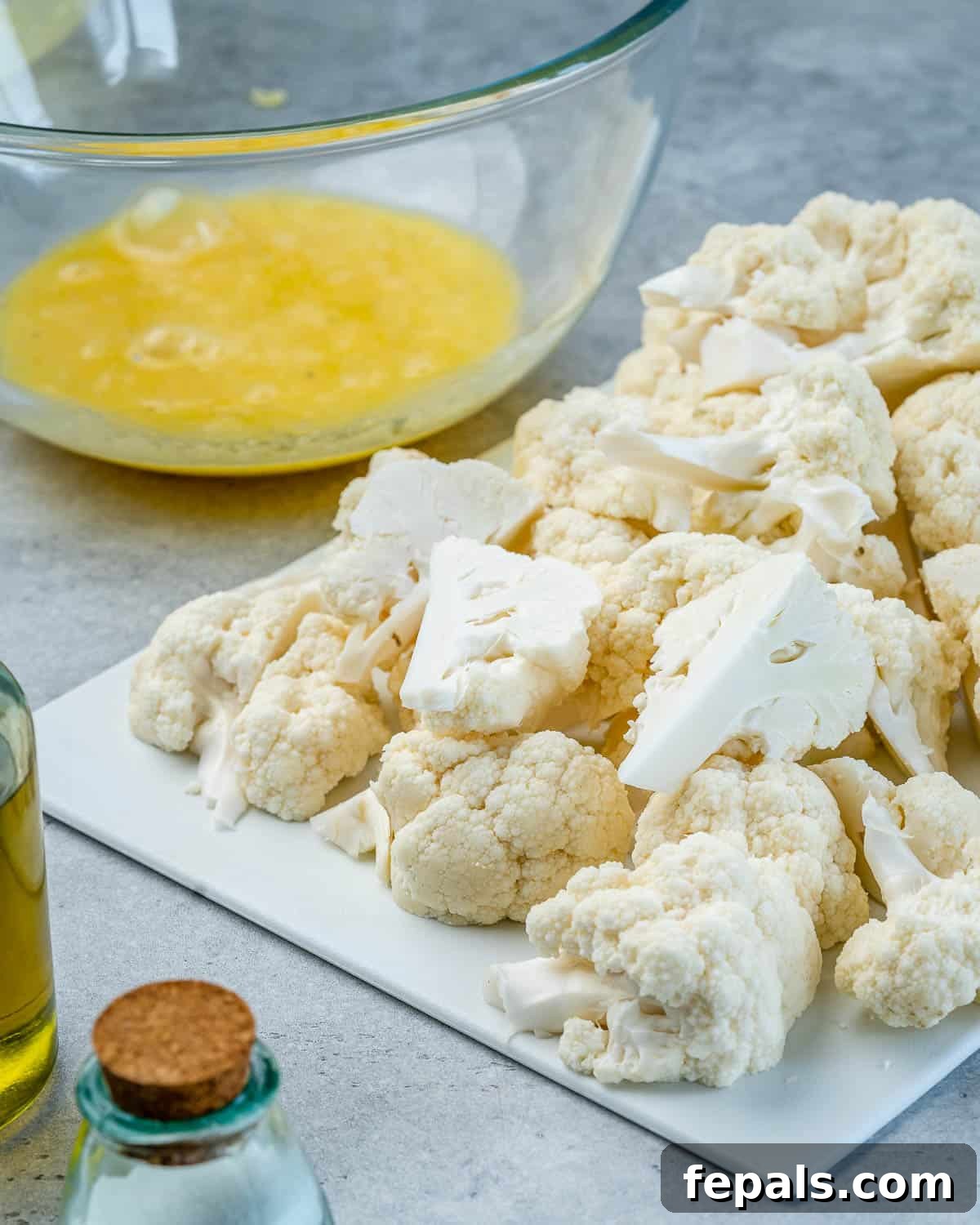 Freshly chopped cauliflower florets on a wooden cutting board, ready for preparation.