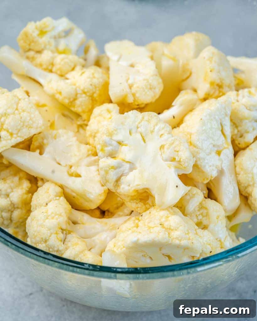 Cauliflower pieces coated evenly in egg and flour mixture, ready for cooking.