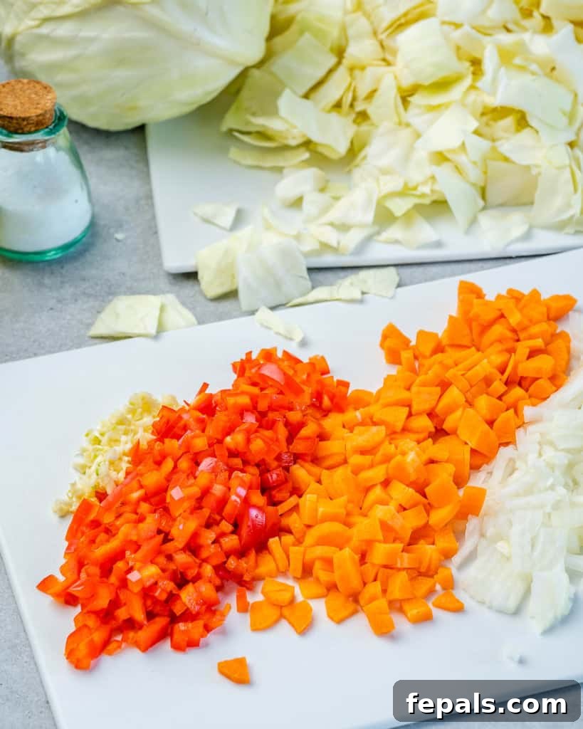 Hearty Unrolled Cabbage Soup 5 Carrots, onions, and bell peppers meticulously chopped on a cutting board, ready for cooking.