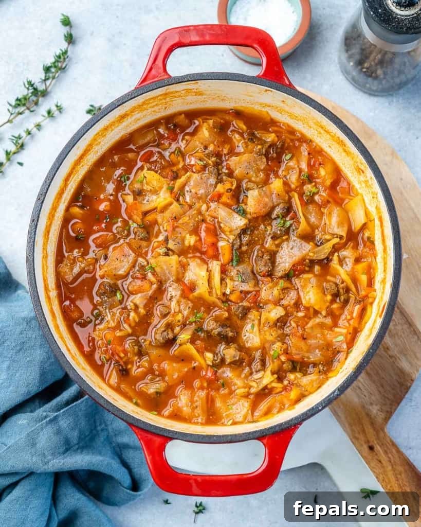 Hearty Unrolled Cabbage Soup 10 Top view of a generously portioned cabbage roll soup in a vibrant red pot, garnished with fresh herbs.