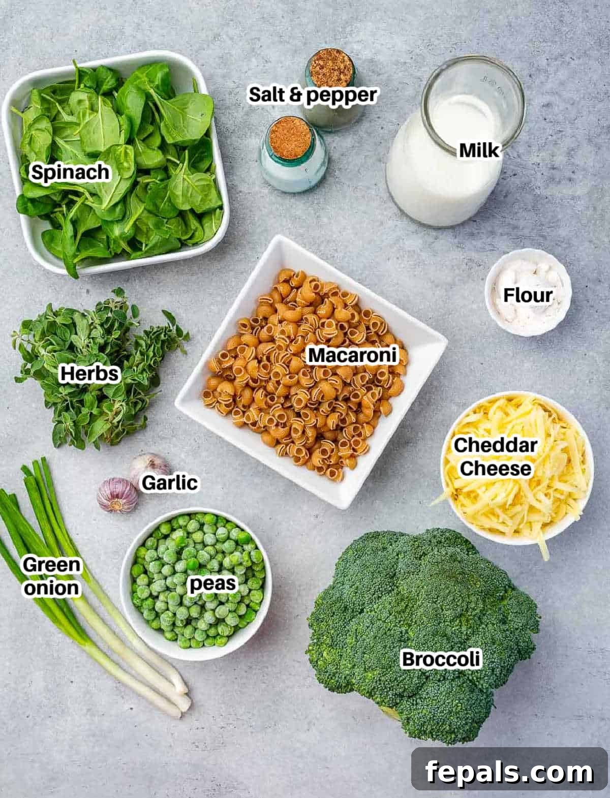 Ingredients laid out for making green mac and cheese, including pasta, vegetables, and cheese.