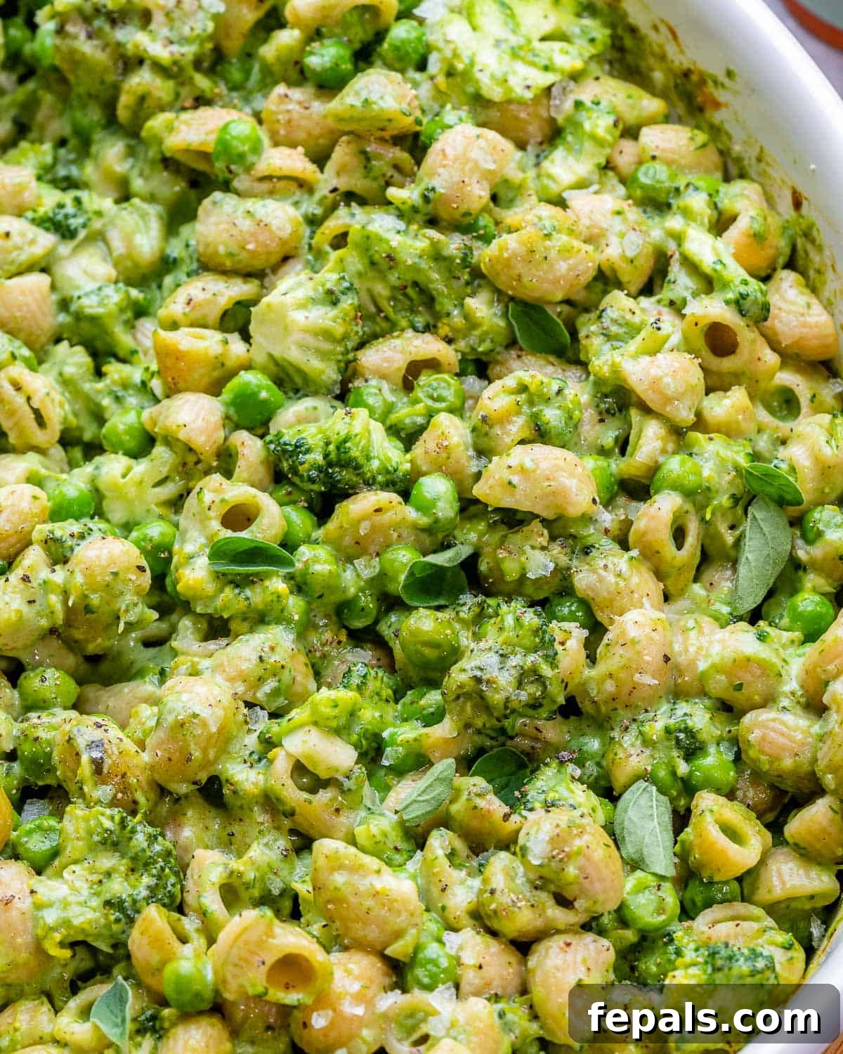 Close-up view of a serving of green mac and cheese, highlighting the vibrant colors and fresh ingredients.