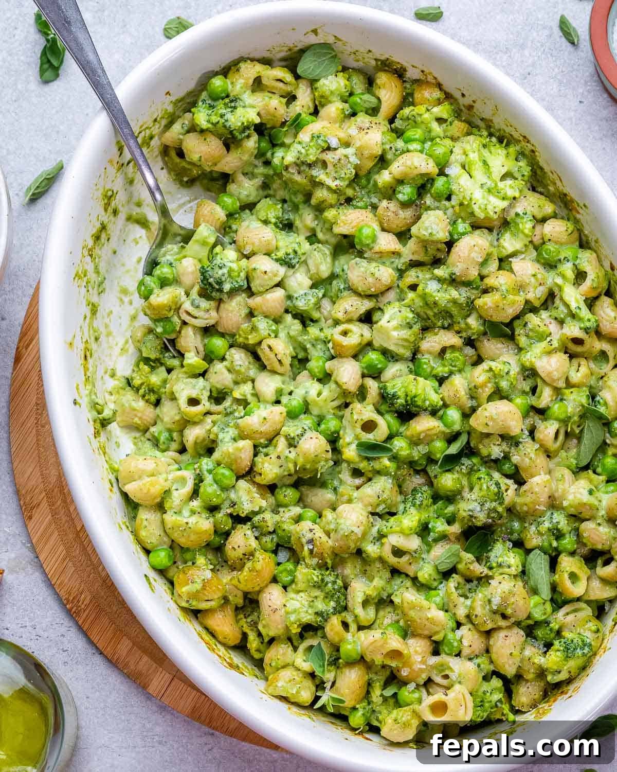 Spoon inside a serving dish of healthy green mac and cheese, ready to be enjoyed.
