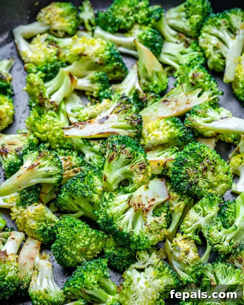 Sautéed broccoli florets cooking in a pan, lightly browned and crisp-tender.