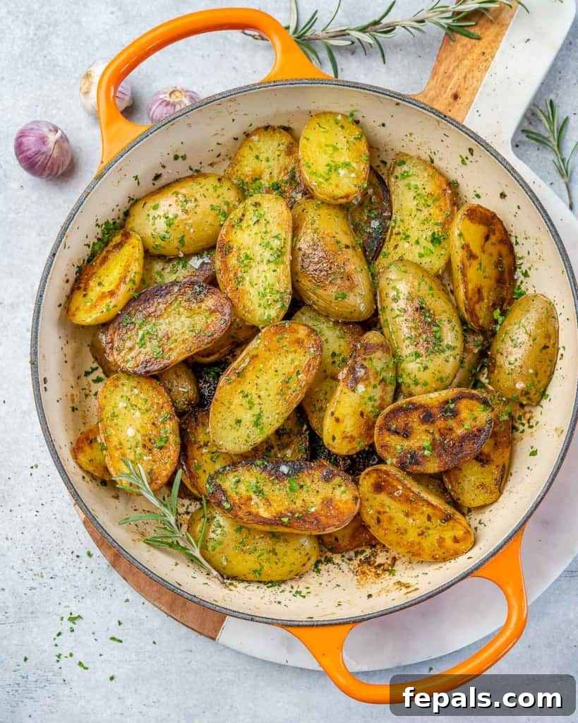 Crispy Garlic Skillet Potatoes 2 Top view of golden pan-roasted garlic baby potatoes in a skillet, garnished with fresh herbs.