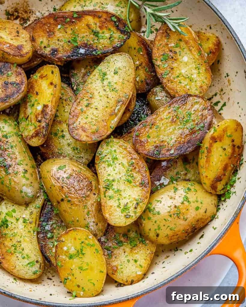 Crispy Garlic Skillet Potatoes 3 Close-up top view of roasted baby potatoes in an orange cast iron skillet, garnished with fresh parsley.