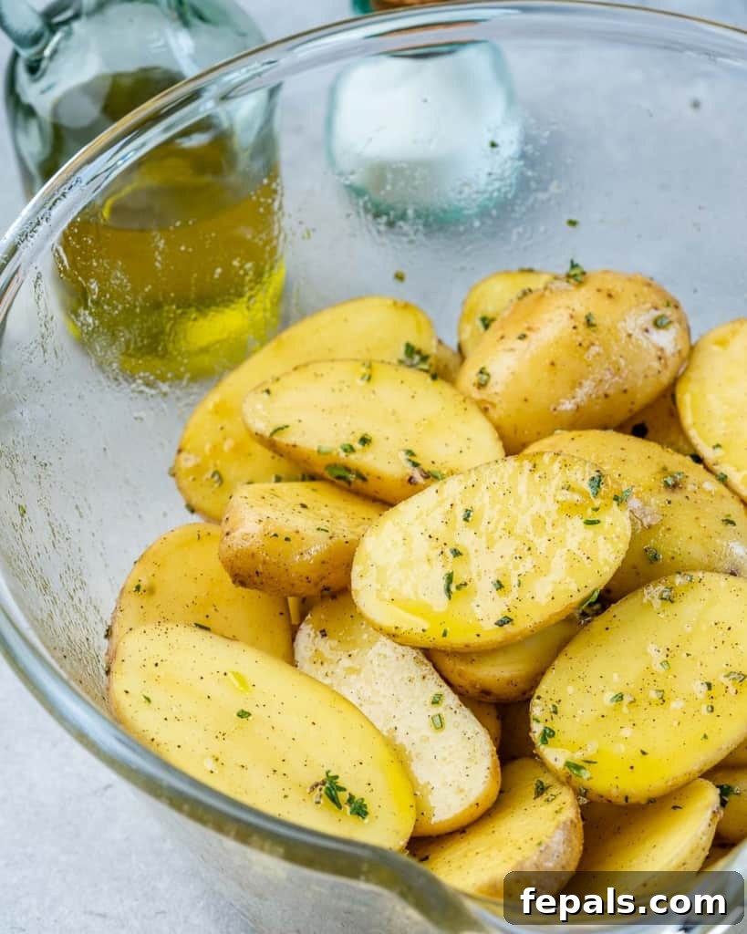 Crispy Garlic Skillet Potatoes 6 Raw baby potatoes coated with herbs, garlic, and oil in a large mixing bowl.