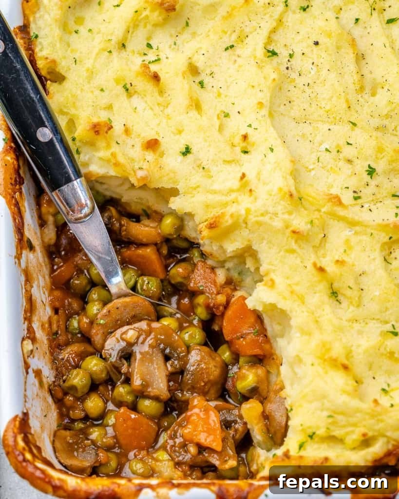 Garden Shepherd's Pie 3 Close-up of a serving of vegetarian shepherd's pie with a spoon, highlighting the rich filling and creamy mashed potatoes.