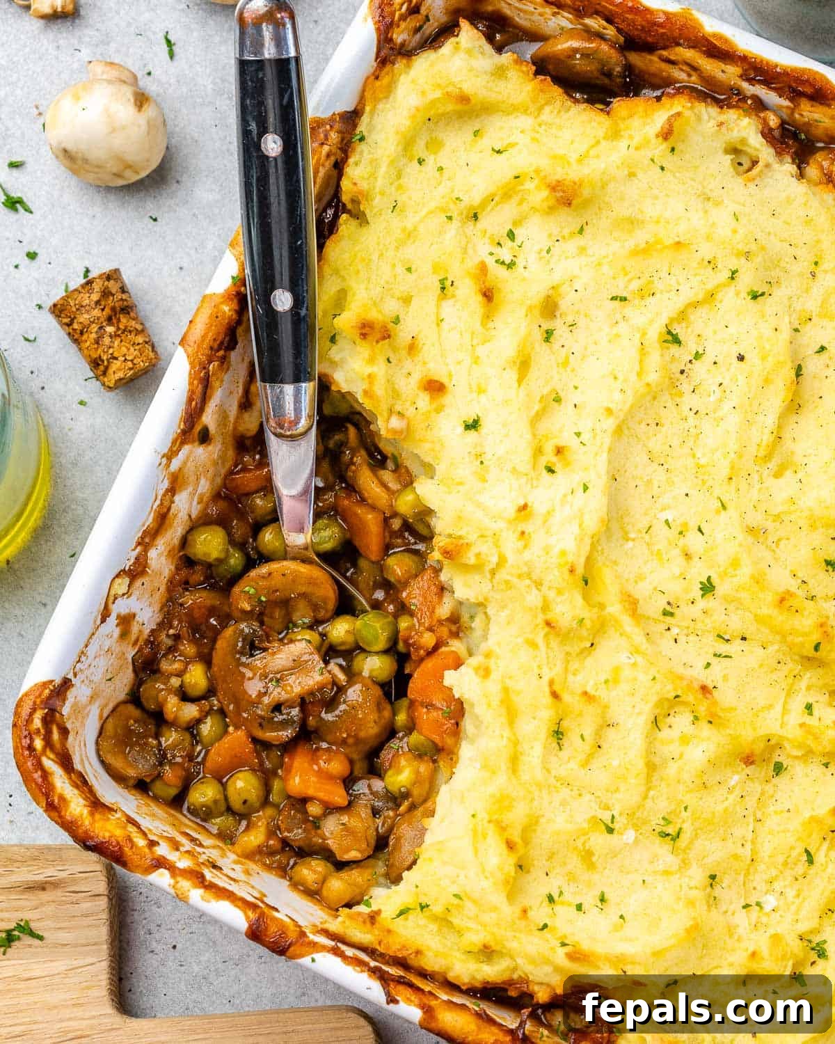 Garden Shepherd's Pie 9 A corner view of a white baking dish with a portion of shepherd's pie already scooped out, revealing the layers.